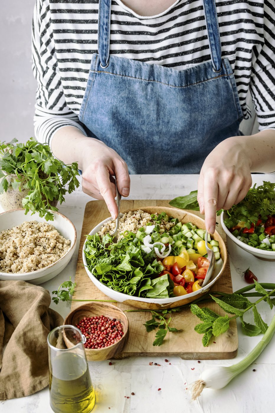 Hands preparing a fresh plant-based bowl in a home kitchen